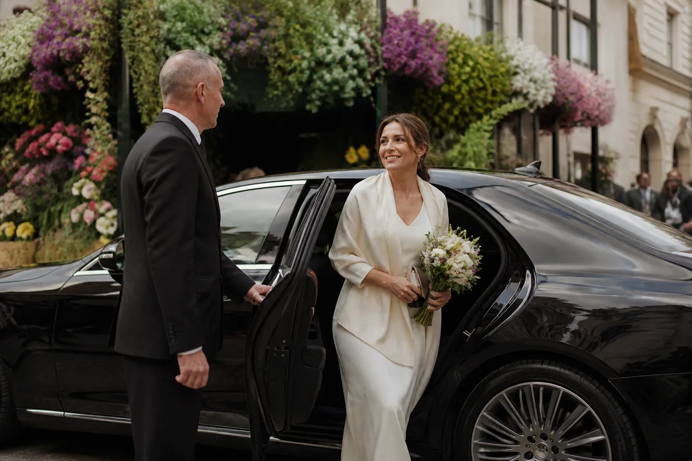 A chauffeur car on a Chelsea street beside the wall of a large garden